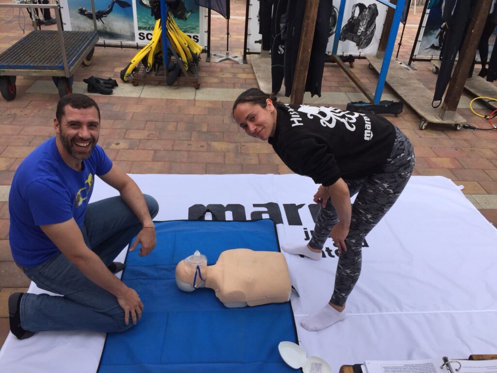 Une élève apprend la réanimation cardio-pulmonaire (RCP) sur un mannequin avec une instructrice lors d'une formation de plongée.