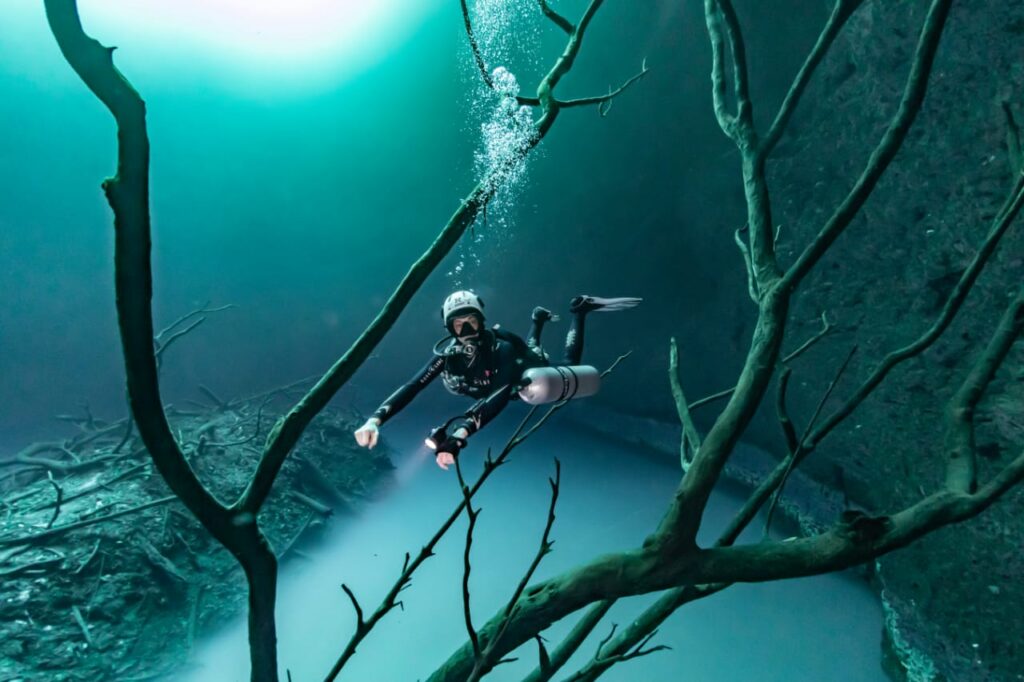 Plongeuse en configuration sidemount explorant le cénote Angelita dans la Riviera Maya, au Mexique, avec un trim parfaitement horizontal.